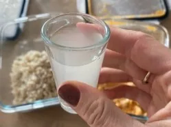 Sklenička kefíru nad miskou s namočenými vločkami